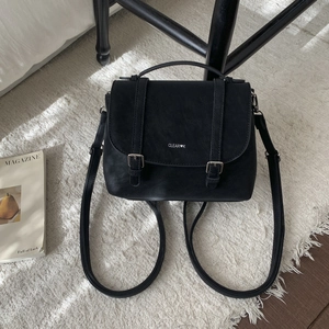 Close-up of black matte leather backpack featuring CLEAR K logo and dual buckle straps
