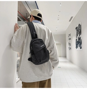 Side view of black plaid crossbody chest bag on model in a minimalist urban corridor