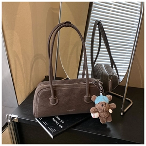 Vue détaillée du sac Boston en daim marron foncé avec un pendentif ours en peluche