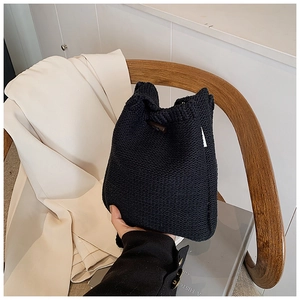 Détail du sac seau en tricot noir montrant la texture tissée et l'étiquette blanche