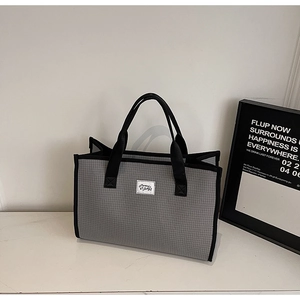 Détail du sac cabas à carreaux gris avec poignées noires et étiquette tissée blanche