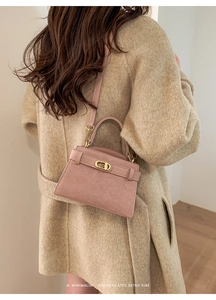 Close-up of pink frosted leather crossbody bag with golden lock on wool coat