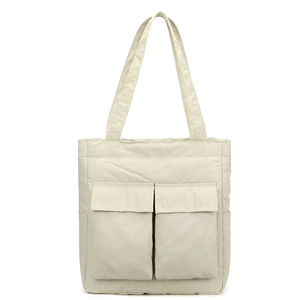 Detail of cream nylon tote bag featuring quilted texture and two large front flap pockets