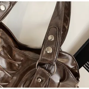 Close-up of vintage dark brown faux leather bag featuring silver studs and metal ring