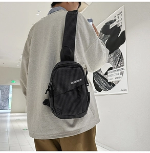 Rear view of a model wearing the black checkered crossbody chest bag in a minimalist hall