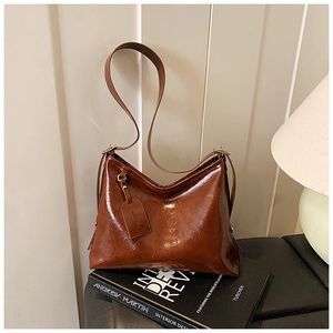 Detailed view of brown oil wax leather tote bag placed on vintage books in a warm setting