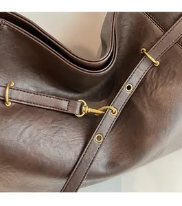 Detail of vintage bronze hardware and reinforced stitching on a brown leather tote bag