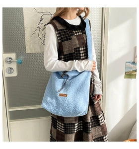 Detail of light blue fuzzy tote bag with drawstring closure and brown leather logo patch