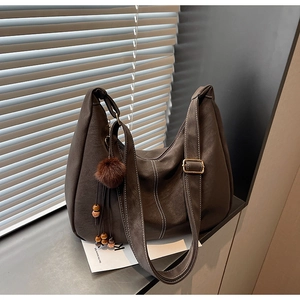 Detail of coffee brown tote bag with white contrast stitching and plush ball charm