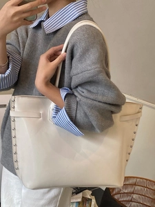 Minimalist creamy white leather tote bag with silver rivet details shown on model