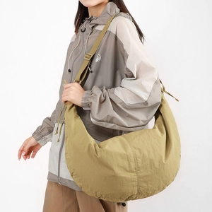 Detail view of khaki nylon crescent crossbody bag with adjustable wide strap on model