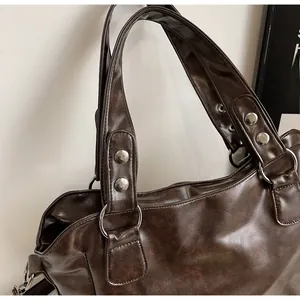 Detailed close-up of dark brown faux leather tote bag with silver metal ring handles