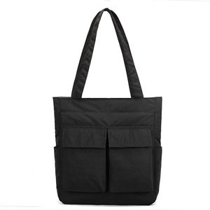 Detail of black utility tote bag showing front flap pockets and durable nylon texture