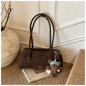 Détail du sac Boston en daim marron foncé avec fermeture éclair argentée et pendentif ours