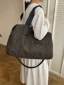 Grande borsa tote con stampa leopardata e tracolla larga mostrata in un ambiente interno
