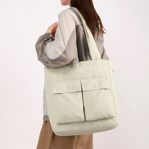 Close-up of large capacity tote bag with dual front flap pockets in light green nylon