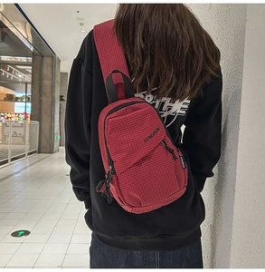 Detail of red checkered crossbody chest bag with double zippers and adjustable strap