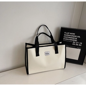 Détail d'un sac cabas minimaliste en toile crème avec poignées et bordures noires