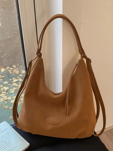 Vintage Hobo-Tasche in Karamell bei Sonnenlicht mit herbstlichem Hintergrunddekor