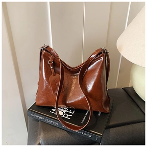 Detail of dark brown oil wax leather hobo bag on books in a cozy indoor setting