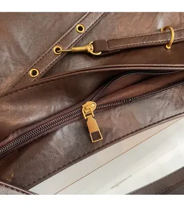 Close-up of vintage gold hardware zipper and smooth brown leather texture on tote bag