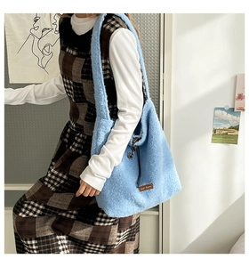 Detail of light blue fuzzy tote bag with drawstring closure and brown leather tag