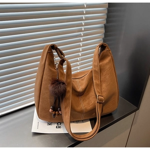 Detail of retro brown faux leather tote with plush charm and wide shoulder strap