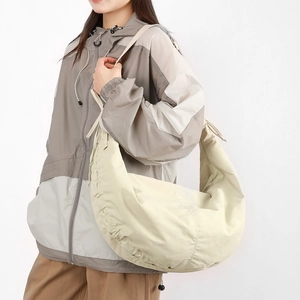Detail view of large nylon dumpling bag featuring side pleats and adjustable shoulder strap