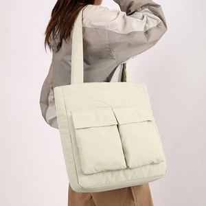 Side view of cream quilted tote bag with two large front flap pockets on model