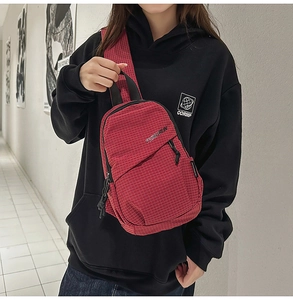 Detail of red checkered crossbody chest bag with adjustable strap and front zipper pocket