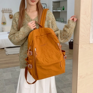 Detailansicht des ingwerfarbenen Nylonrucksacks mit Seitenschnalle und Bestickung