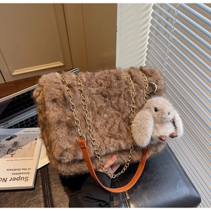 Dettaglio della borsa tote in peluche marrone con catena dorata e ciondolo a forma di coniglio