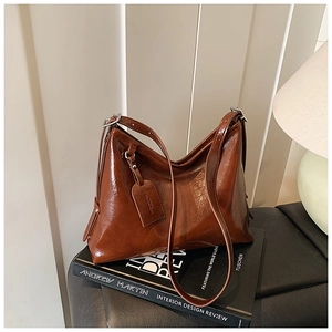 Detail of dark brown polished leather shoulder bag with silver buckle on a book