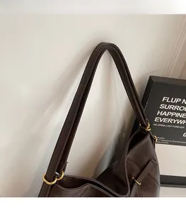 Detail of dark brown leather tote strap with high-quality golden metal rings and stitching