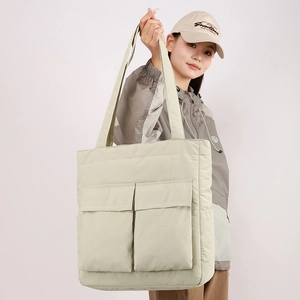 Detail view of large rice green tote bag featuring two front utility flap pockets