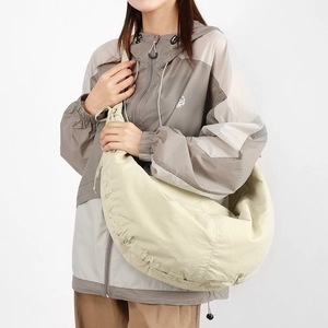 Detail view of cream nylon crescent bag with adjustable side drawstring on a model