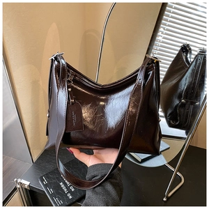 Detail of dark brown patent leather bucket bag with retro texture and branded tag