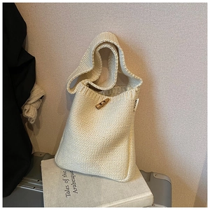 Détail du sac seau en maille crème montrant le tissage texturé et le fermoir en bois