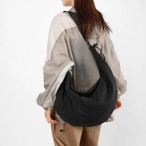 Detailed side view of a large black nylon crescent crossbody bag with adjustable strap