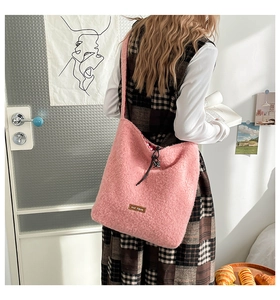 Detail of pink faux fur tote bag with drawstring closure and logo patch on checkered dress