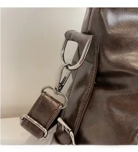 Detailed close-up of glossy brown leather tote with shiny silver metal D-ring and lobster clasp