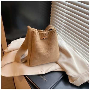 Détail du sac seau en tricot kaki avec fermoir en bois et texture tressée fine