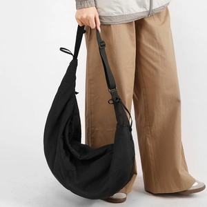Detail of black nylon crescent bag with wide adjustable shoulder strap on model