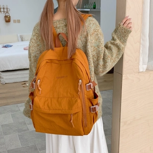 Detail eines orangen Nylonrucksacks mit seitlichen Schnallen und Doherty-Stickerei