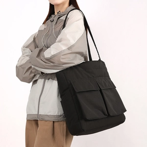 Detailed view of black large capacity tote bag with front pockets on model
