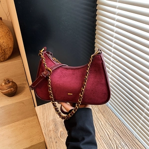 Bolso de media luna retro de ante burdeos con cadena dorada bajo luz natural