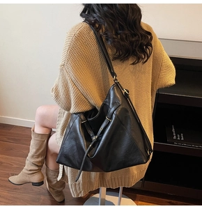 Detail of a large black leather tote bag with adjustable strap and metal buckle finish