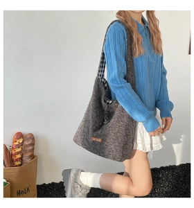 Detail of grey felt tote bag with a leather label and stylish black drawstring closure
