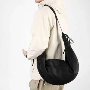Side view of large black nylon dumpling bag with adjustable strap and drawstring detail