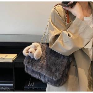 Dettaglio borsa tote in peluche grigio scuro con catena dorata e ciondolo a coniglio